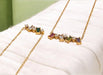 Two gold necklaces with gemstones on a white surface
