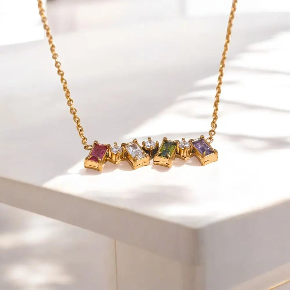 Gold necklace with colorful gemstones on a white surface