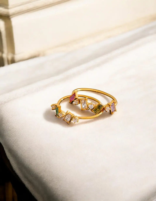 Gold ring with colorful gemstones on a white surface
