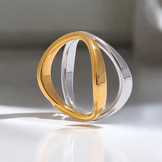 Two gold rings stacked on a reflective surface with a neutral background