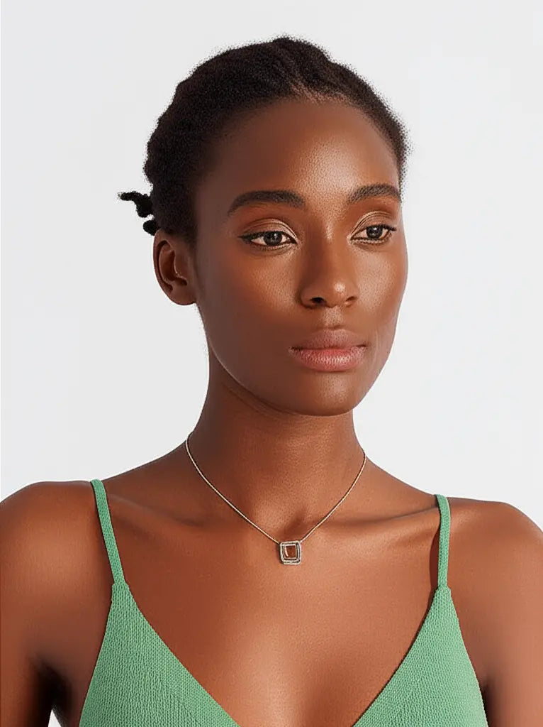 Woman wearing a green top and necklace on a plain background