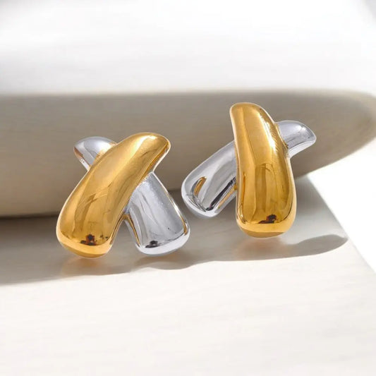 Pair of gold and silver earrings on a white surface