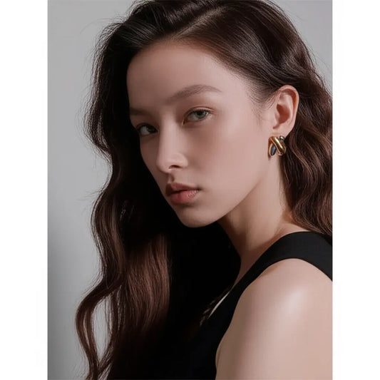 Woman wearing gold earrings with a neutral background