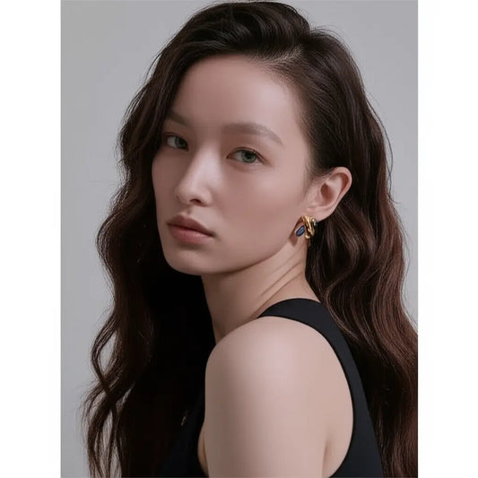 Woman with long dark hair wearing a black sleeveless top against a neutral background