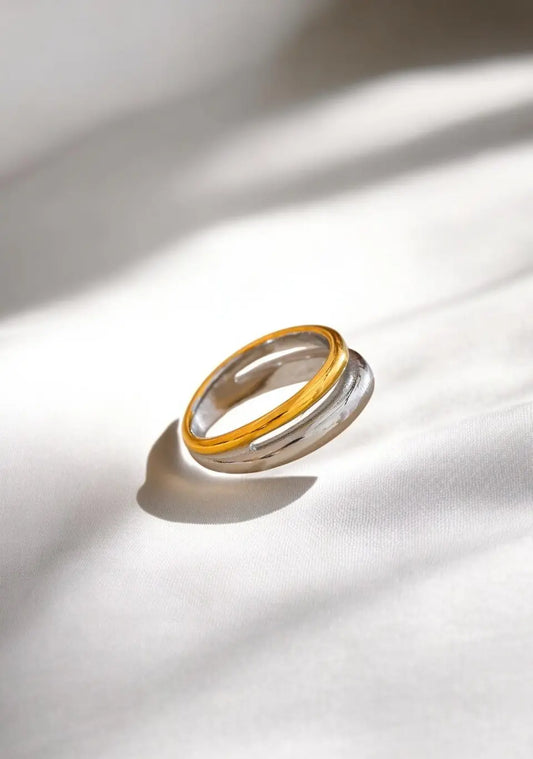 Two gold and silver rings stacked on a white fabric background