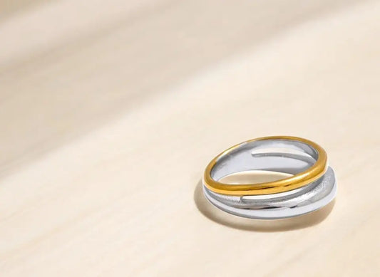 Two gold and silver rings stacked on a beige background